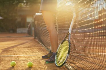 Weibliche Athletin steht mit Tennisschläger und Ball auf einem Sportplatz an einem sonnigen Tag - OYF00508