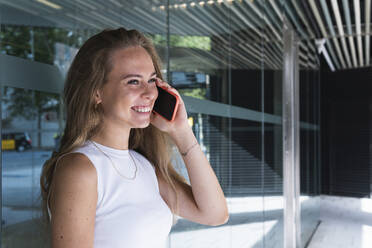 Glückliche junge Geschäftsfrau im Gespräch mit einem Smartphone - PNAF02330