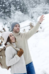 Freund zeigt beim Wandern mit Freundin im Winter auf den Boden - HHF05670