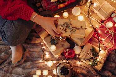 Young woman holding wrapped gift during Christmas at home - EGHF00177