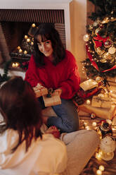 Lächelnde Frau gibt Weihnachtsgeschenk an Freundin zu Hause - EGHF00182