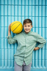 Smiling boy with sports ball in front of pattern wall - RCPF01271