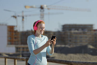 Woman using mobile phone while listening music - AANF00071