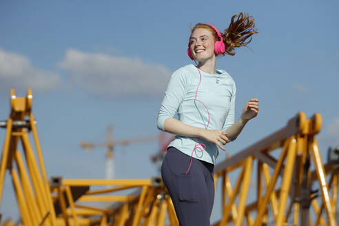 Rothaarige Frau joggt an einem sonnigen Tag - AANF00078