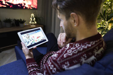 Junger Mann im Gespräch mit einer Frau über ein digitales Tablet zu Weihnachten - ABIF01624