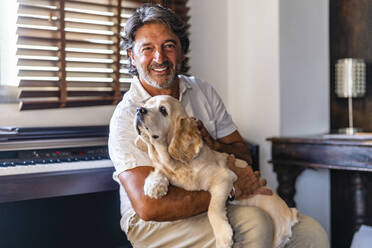 Glücklicher Mann, der seinen Hund streichelt, während er zu Hause sitzt - DLTSF02208