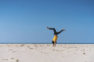 Mann macht Handstand am Strand an einem sonnigen Tag - AFVF09188