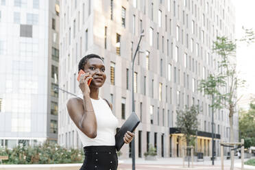 Female freelancer talking on smart phone in city - JCZF00837