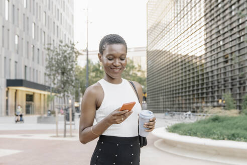 Businesswoman with disposable coffee cup using mobile phone in city - JCZF00841