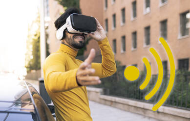 Lächelnder Mann mit Virtual-Reality-Headset durch WiFi-Symbol - JCCMF03865