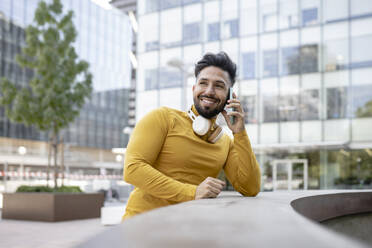 Smiling man talking on mobile phone in city - JCCMF03885