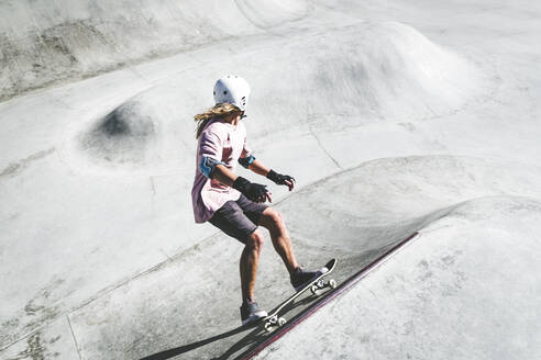 Sportler, der an einem sonnigen Tag im Skateboard-Park skatet - OMIF00056