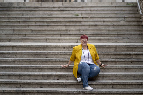 Happy mature woman sitting on steps - OCMF02224