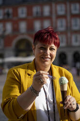 Smiling mature woman eating ice cream - OCMF02233