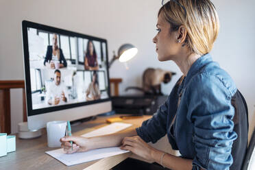 Female vlogger with note pad during video conference at home - JSRF01621