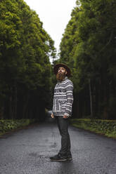 Male tourist wearing hat while standing on road - AFVF09230