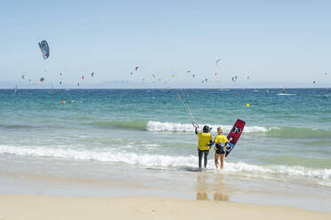 Trainerin mit Kiteboard, die eine Frau an einem sonnigen Tag unterrichtet - PGF00805