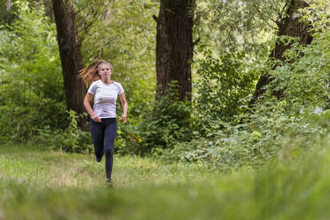 Junge Sportlerin beim Laufen im Wald - STSF03042