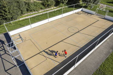 Sportsman playing basketball with female friend during sunny day - STSF03045
