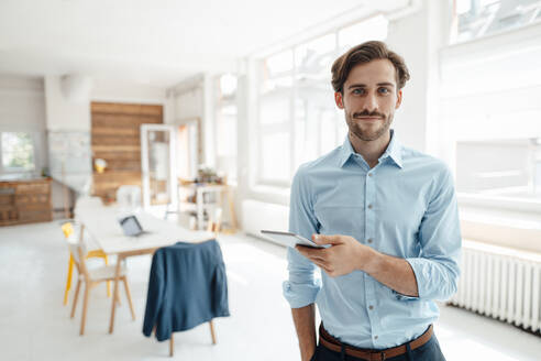 Männlicher Geschäftsmann mit digitalem Tablet im Büro - KNSF08952