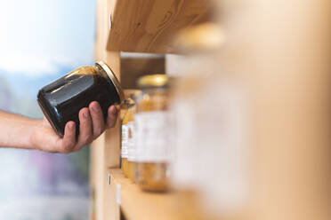 Männlicher Ladenbesitzer hält Honigglas am Regal - JAQF00718