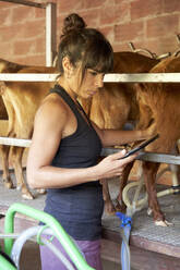 Female farmer using digital tablet in goat farm - VEGF04997