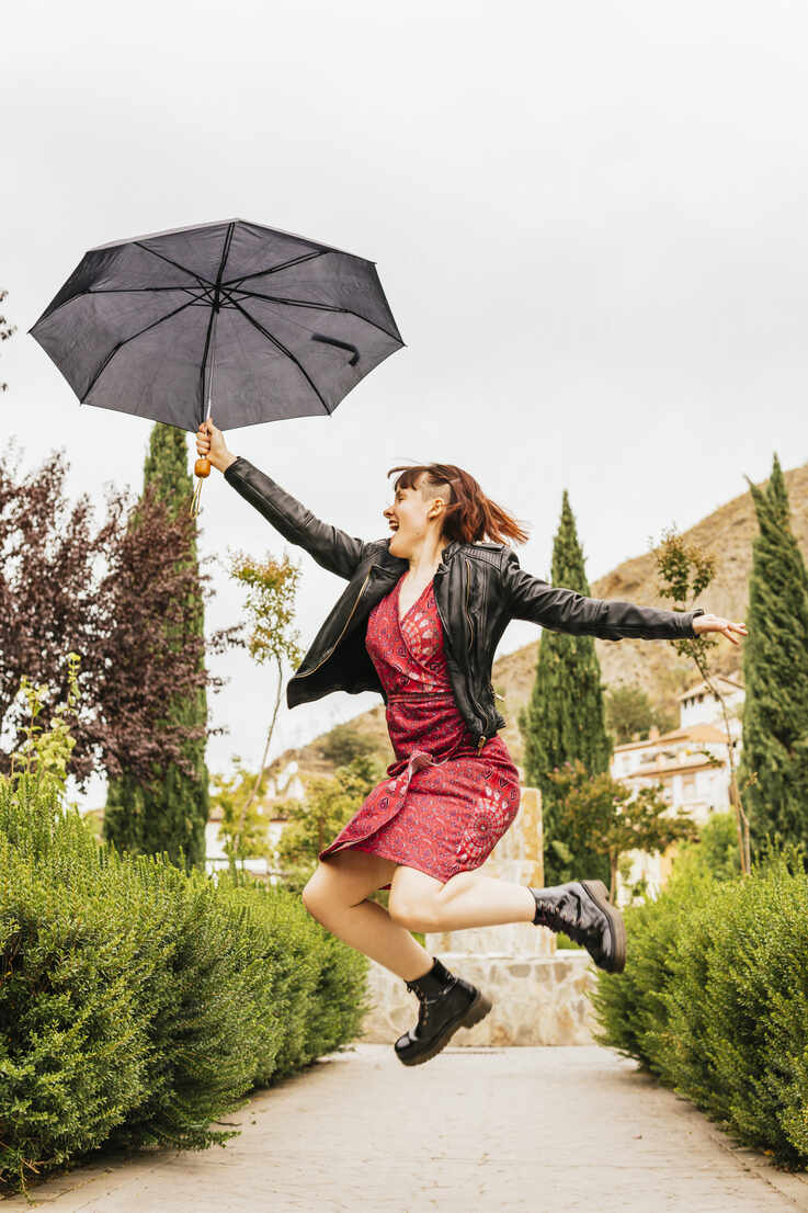 Elegant Urban Escape: A Young Lady With Umbrella Poses in a Vibrant  Cityscape