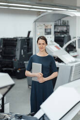 Weibliche Fachkraft mit digitalem Tablet in der Werkstatt stehend - KNSF08980