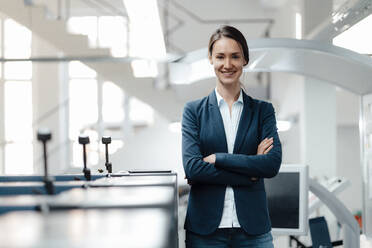 Businesswoman with arms crossed standing in industry - KNSF09001