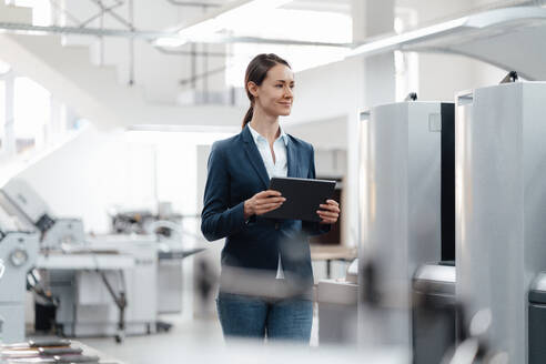 Female business professional holding digital tablet in industry - KNSF09005