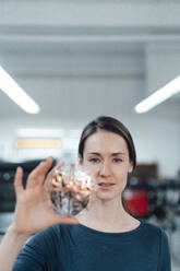 Female design professional holding 3D drone in workshop - KNSF09029
