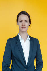 Geschäftsfrau stehend vor gelbem Hintergrund - KNSF09035