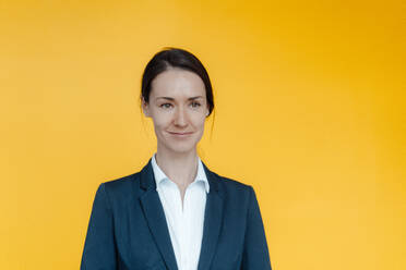 Lächelnde weibliche Business-Profi gegen gelben Hintergrund - KNSF09037