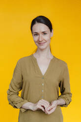 Lächelnde Geschäftsfrau vor einem gelben Hintergrund - KNSF09051