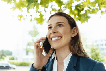 Happy young businesswoman with brown hair talking on smart phone - GUSF06475