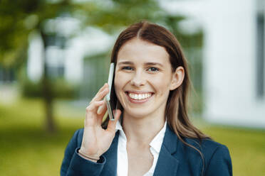 Happy young businesswoman with brown hair talking on mobile phone - GUSF06480