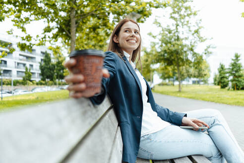 Geschäftsfrau mit Einweg-Kaffeebecher auf einer Bank sitzend - GUSF06482