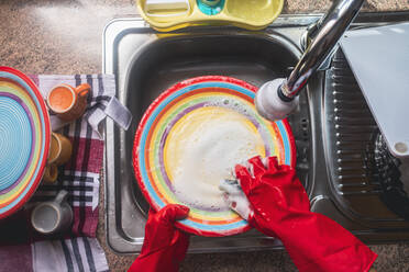 Reife Frau mit Handschuhen beim Geschirrspülen zu Hause - SIPF02381