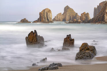 Spektakuläre Szenerie mit schäumenden Meereswellen, die raue Felsformationen verschiedener Formen am wilden Strand von Geirua in Asturien Spanien umspülen - ADSF30330