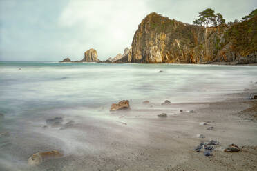 Spektakuläre Szenerie mit schäumenden Meereswellen, die raue Felsformationen verschiedener Formen am wilden Strand von Geirua in Asturien Spanien umspülen - ADSF30331