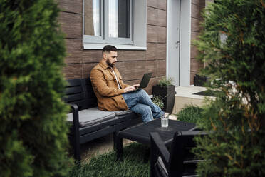 Businessman working on laptop at patio - VPIF04899