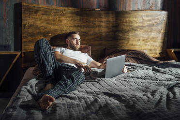 Mann benutzt Laptop auf dem Bett zu Hause - VPIF04915