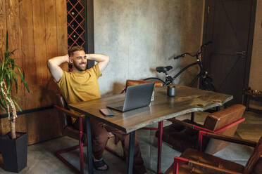 Entspannter männlicher Berufstätiger, der während einer Videokonferenz über einen Laptop zu Hause lächelt - VPIF04940