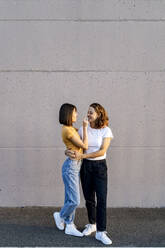 Young lesbian couple standing on footpath - GIOF13546