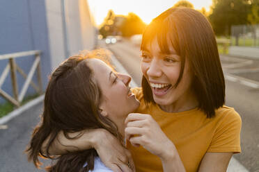 Happy woman with arm around girlfriend during sunset - GIOF13564
