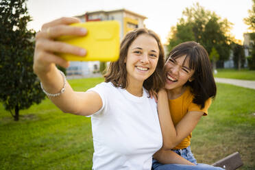 Lächelnde Frau nimmt Selfie mit Freundin durch Smartphone - GIOF13568