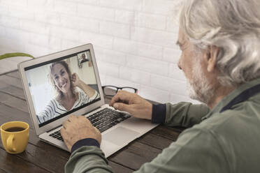 Senior man talking with woman through video call at home - SIPF02388