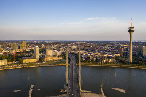 Deutschland, Nordrhein-Westfalen, Düsseldorf, Luftaufnahme der Rheinkniebrücke in der Abenddämmerung mit Rheinturm im Hintergrund - TAMF03250