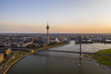 Deutschland, Nordrhein-Westfalen, Düsseldorf, Luftaufnahme der Rheinkniebrücke in der Abenddämmerung mit Rheinturm im Hintergrund - TAMF03251