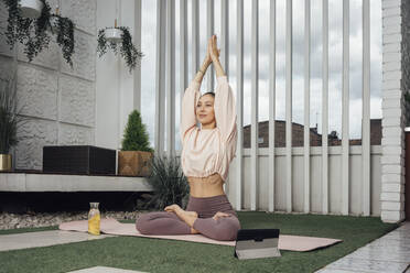 Mittlere erwachsene Frau mit digitalem Tablet, die auf der Terrasse Yoga übt - VPIF04969